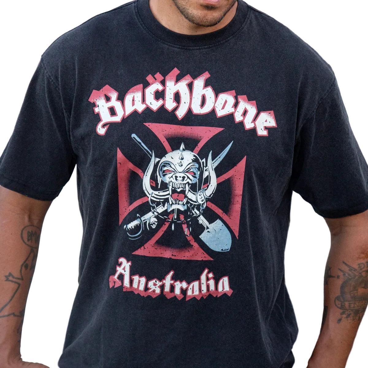 Person wearing a black Backbone Road Crew Vintage T-Shirt, crafted from premium cotton, featuring a horned skull and crossed swords over a red Iron Cross design.