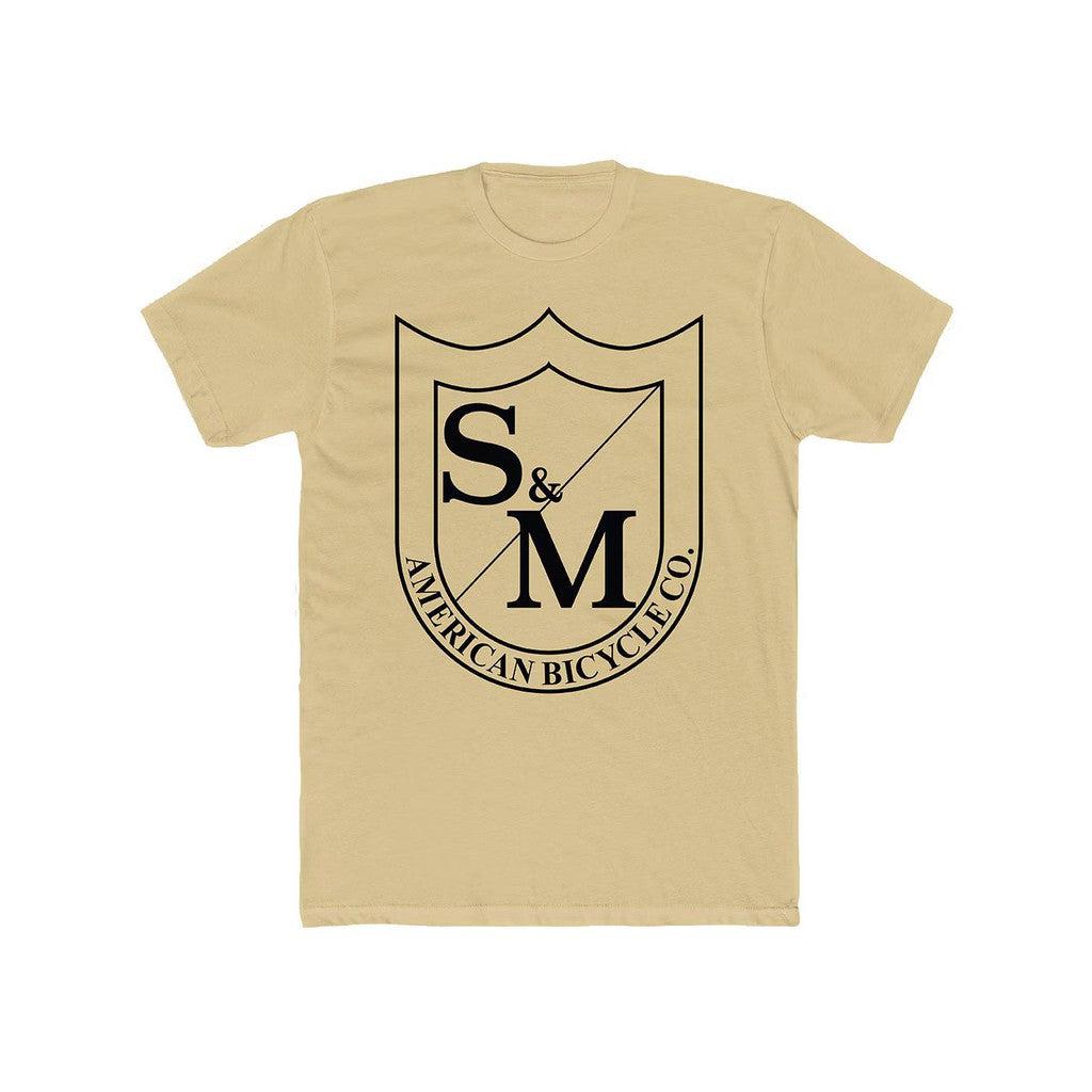 The S&M Big Shield T-Shirt is an oversized beige tee made from soft combed ring-spun cotton, with a large black shield logo and "S&M American Bicycle Co." printed on the front for comfort and standout style.