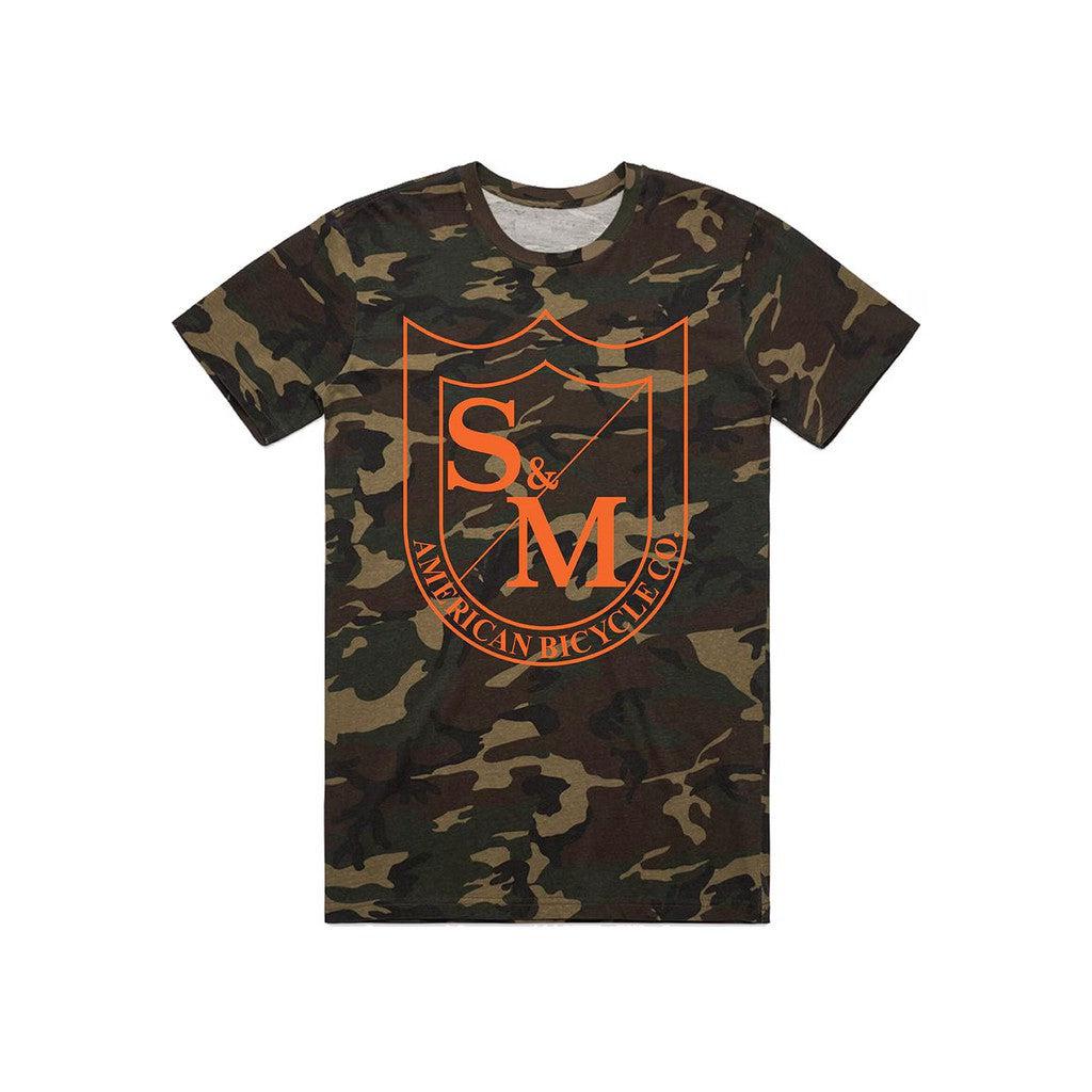 The S&M Big Shield T-Shirt features an orange "S&M American Bicycle Co." crest logo on the front, is made from soft combed ring-spun cotton, and is shown on a white background.