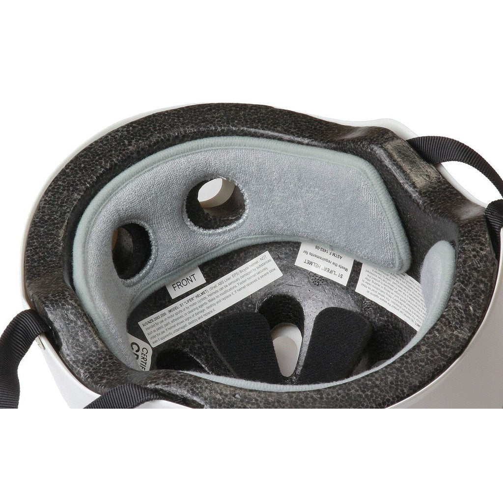 A close-up of the interior of a white bicycle helmet, showing grey padding, ventilation holes, and adjustable black straps. Labels with product and safety information are visible, alongside an S-One Helmet Wide Terry Cloth Liner that ensures comfort on every ride.