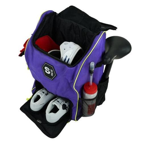 An S1 Helmet / Gear Backpack holds a pair of white shoes, a red towel, and a water bottle in the side mesh pocket, plus features an open compartment for storage.