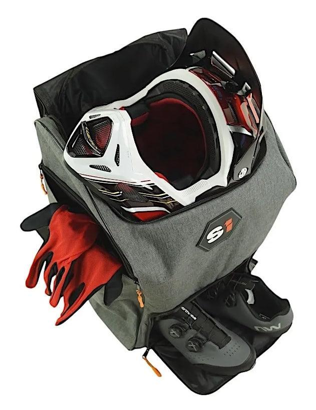 The S1 Helmet / Gear Backpack in gray holds a motorcycle helmet, red gloves, and black cycling shoes, all neatly organized in separate compartments.