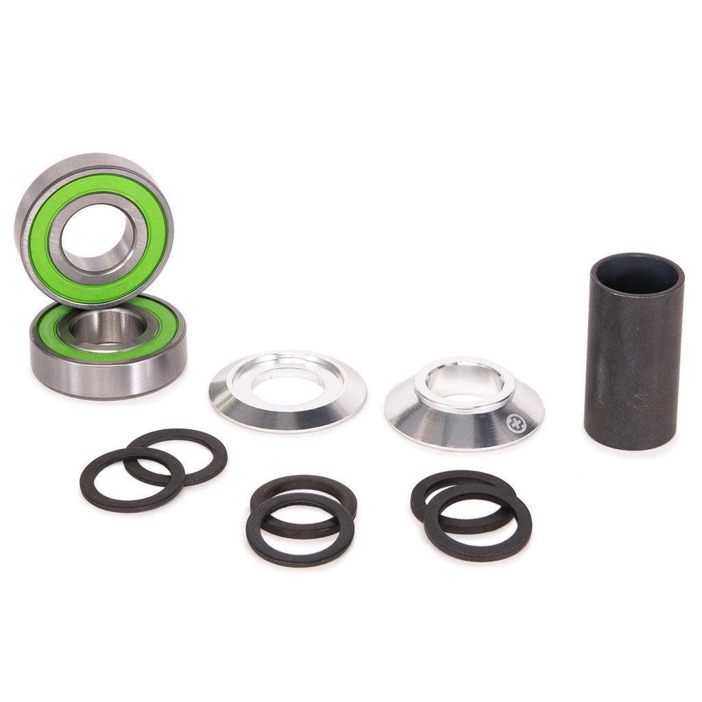 A Salt Plus Echo Mid Bottom Bracket with green accents, metal rings, rubber O-rings, and alloy CNC cones arranged on a white surface.