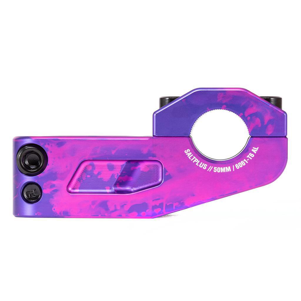 The Salt Plus Manta Top Load Stem, made from CNC 6061-T6 alloy, features a vibrant purple and pink anodized finish. It includes Shark Tooth Clamping for secure grip, as well as distinct bolt holes and branding for a striking appearance.