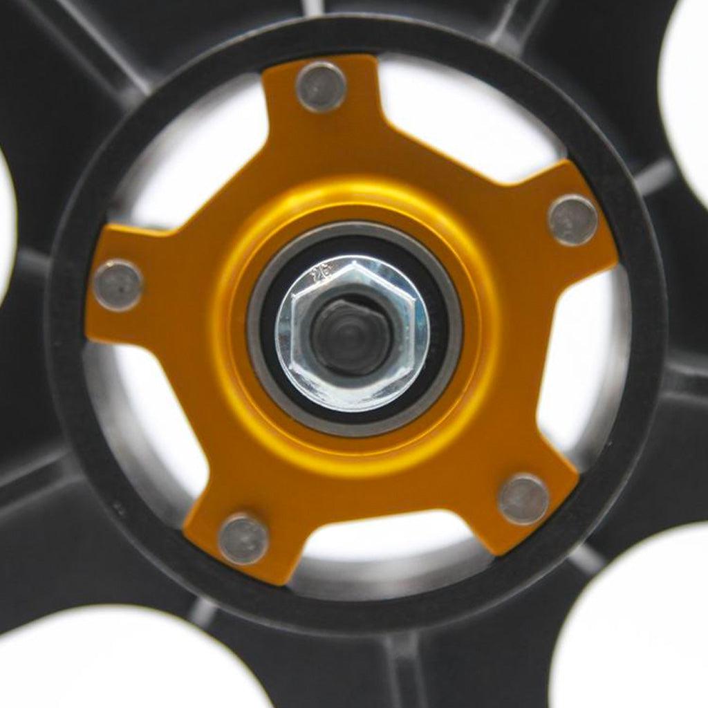 The Skyway 24 Inch Graphite Flanged 7 Spoke Wheels feature a detailed close-up of a metallic wheel hub with an intricate radial design. At the center, a silver bolt is accentuated by a yellow star-shaped element, all elegantly set against a sleek black background.