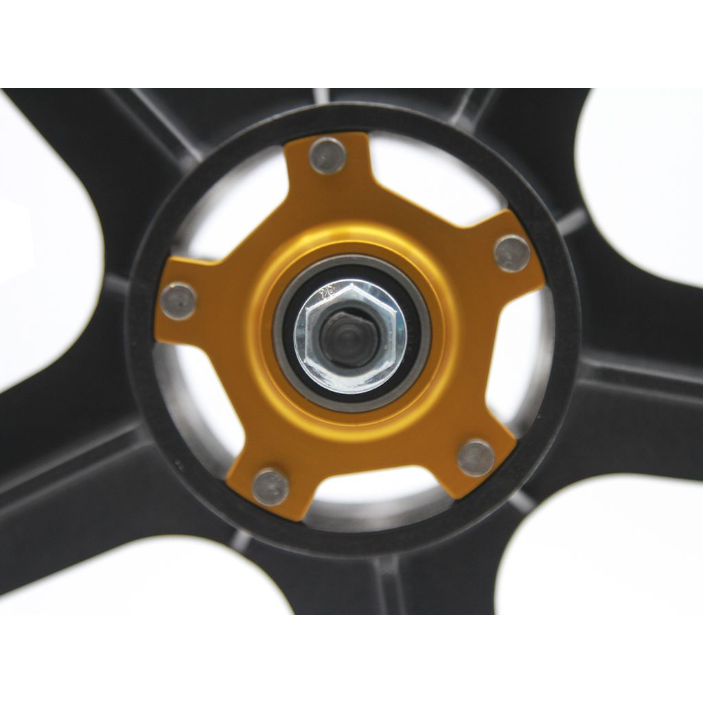 Close-up of the Skyway Tuff Graphite Gold Rivet Wheel Set's hub, showcasing its golden central cog and five silver bolts. The black spokes, made from Graphite Composite, radiate outward from the hub, combining durability with a sleek design.