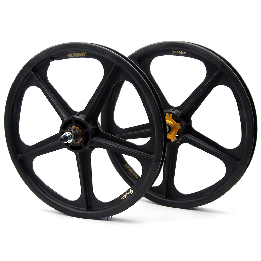 The Skyway Tuff Graphite Gold Rivet Wheel Set (Cassette Model) features two black bicycle wheels, each featuring five sleek spokes, crafted from graphite composite and accented with golden hubs.