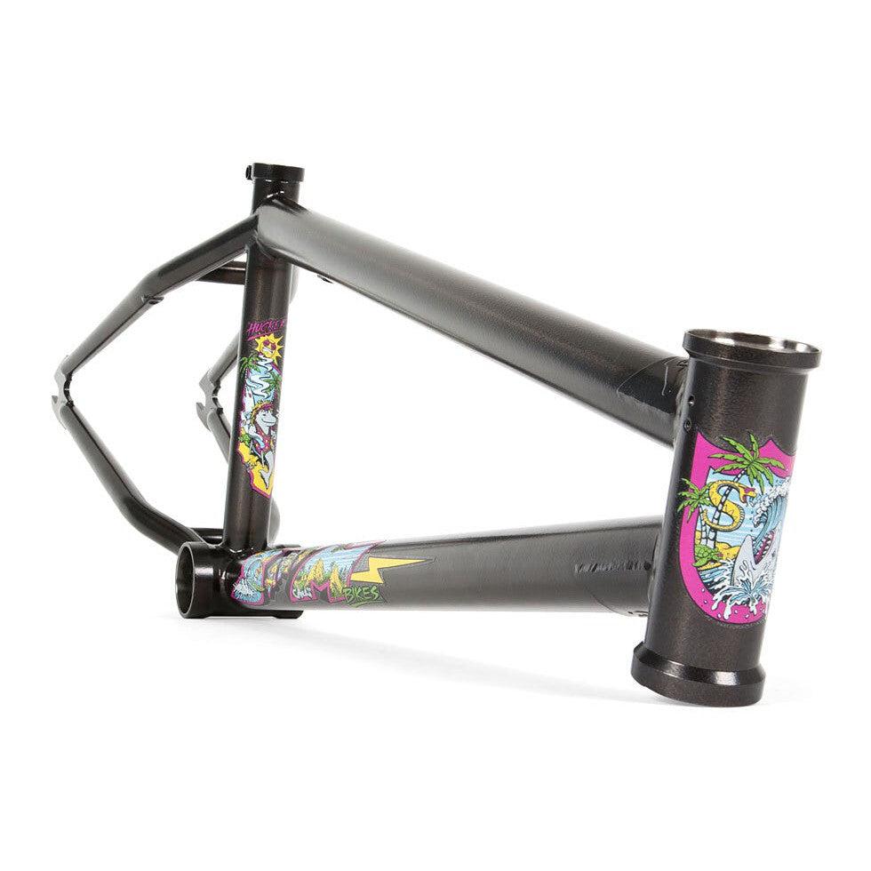 The S&M Hucker Frame (Mike Hucker Signature) is a matte black chromoly BMX frame, decorated with vibrant palm tree and cartoon-style graphic decals on the head tube and downtube.
