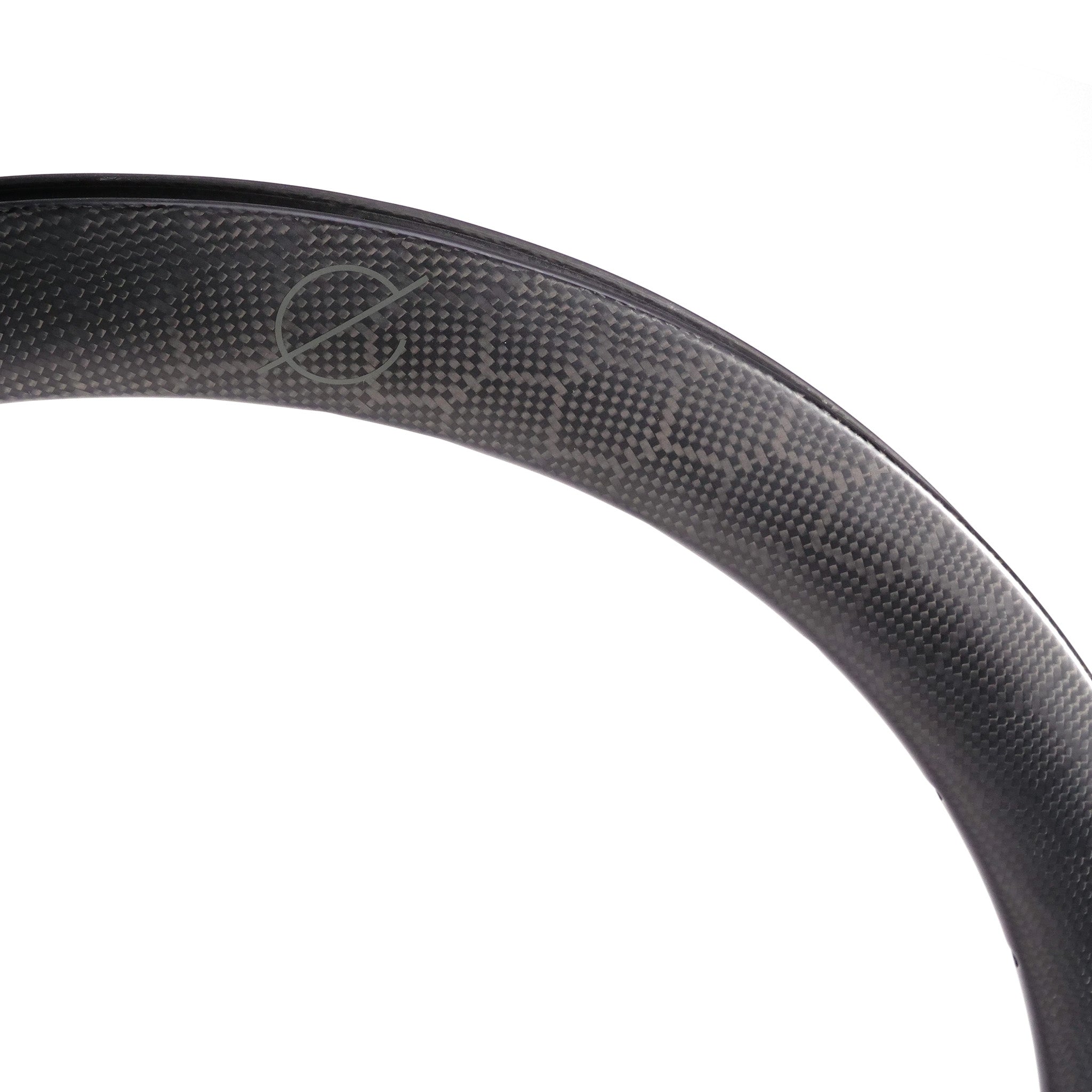 Close-up of a Spectre V2 Carbon Fiber 451 28H Brakeless Rim, highlighting its subtle textured pattern with precision 4D drilled holes and a discreet logo.