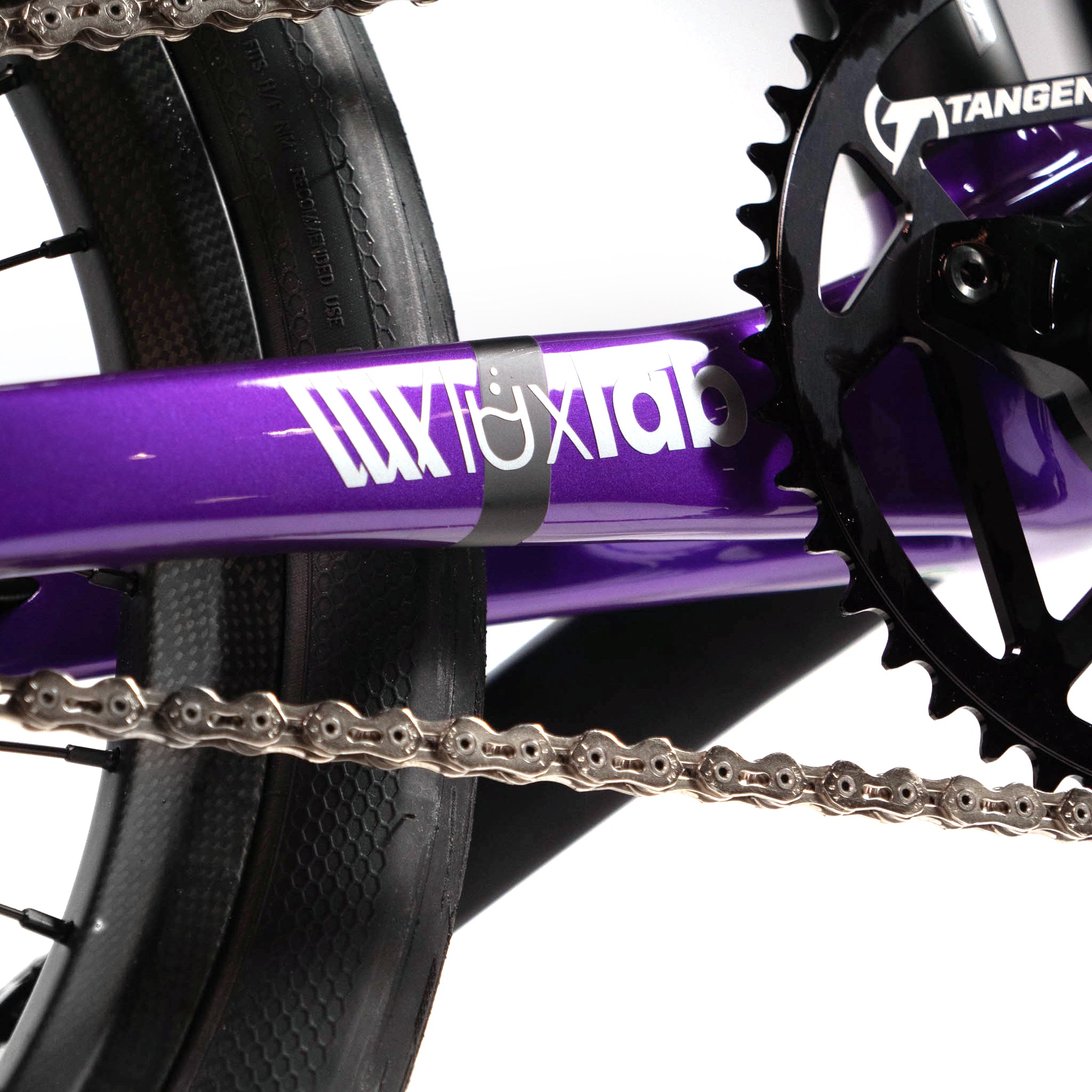 Close-up of a bicycle chain and Avian gear on a purple Speedco Velox Evo Pro XXXL Custom Bike frame with the text "Lux Lab.