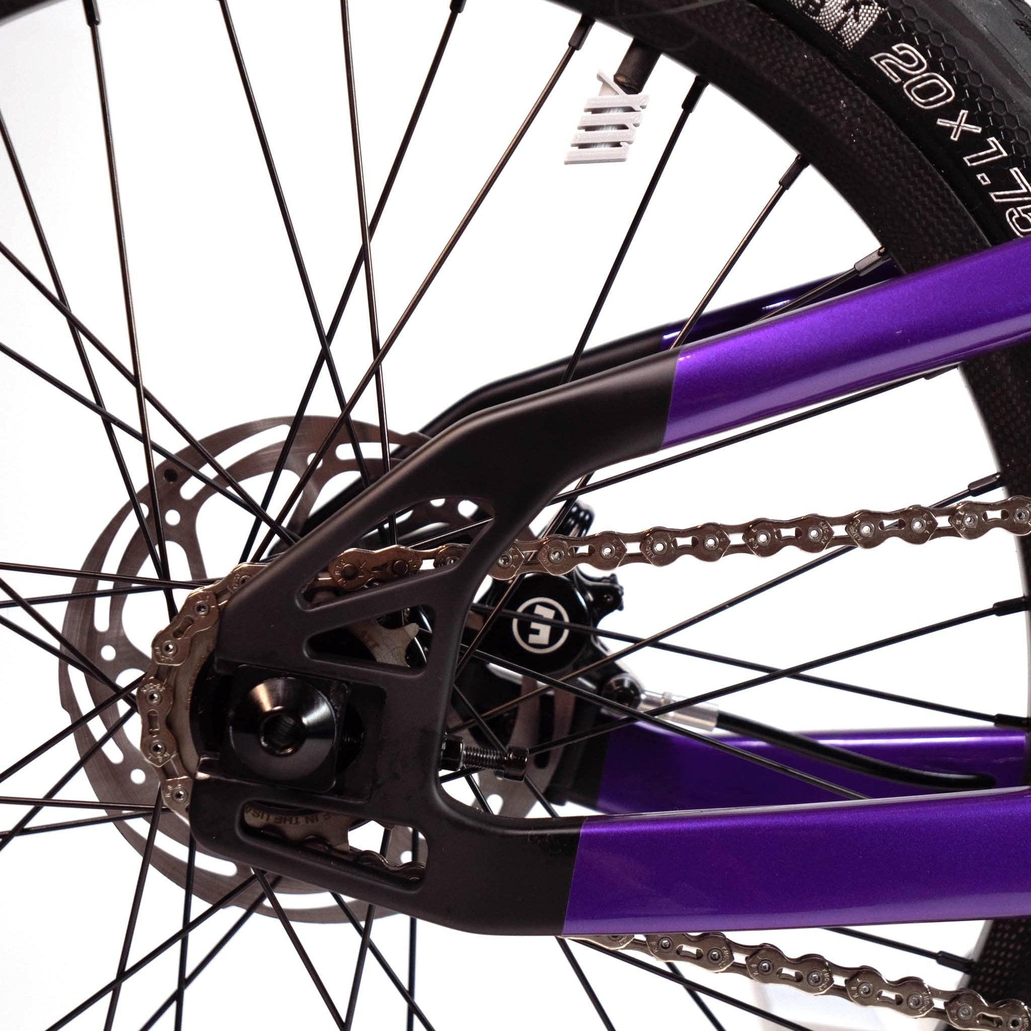 Close-up view of the rear wheel, chain, and disc brake rotor of a purple Speedco Velox Evo Pro XXXL Custom Bike. The image highlights the spokes and part of the bike frame.