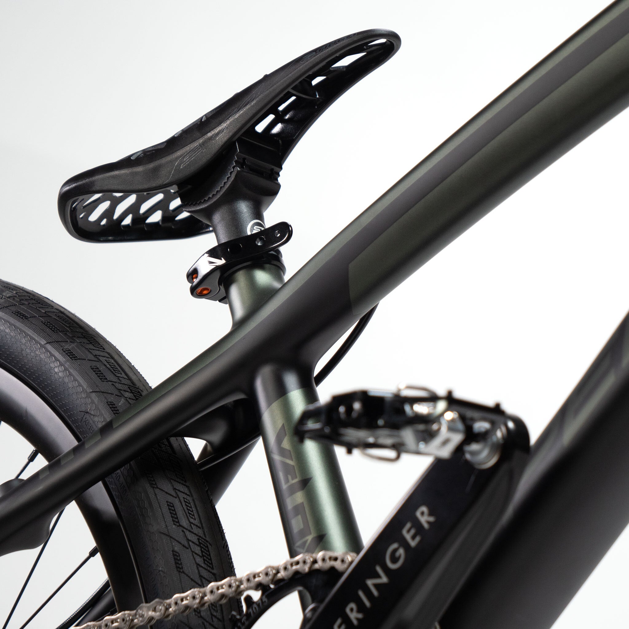 Close-up of a sleek Speedco Velox Pro XL Cruiser Custom Bike in black, showcasing its distinct seat, tire, and pedal components, set against a light background.