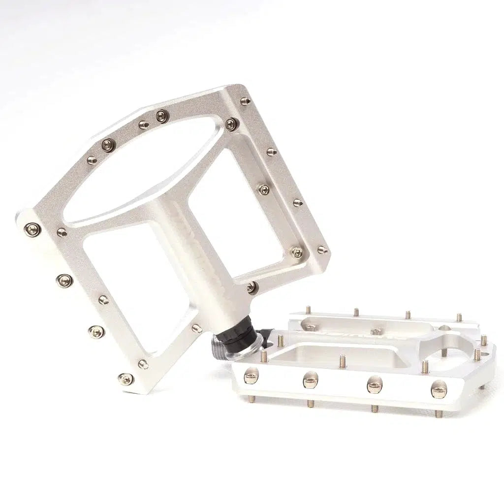 A pair of Stay Strong FORCE Pro Platform Pedals with multiple grip pins on a white background. One pedal is standing upright while the other lies flat.