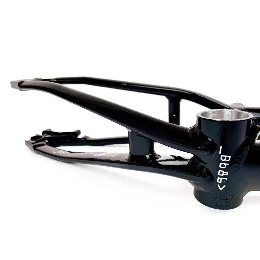 A close-up view of a black aluminium race frame shows the bottom bracket shell with a serial number on it. The Staystrong V5 Disc Pro Cruiser Frame is positioned horizontally against a white background.