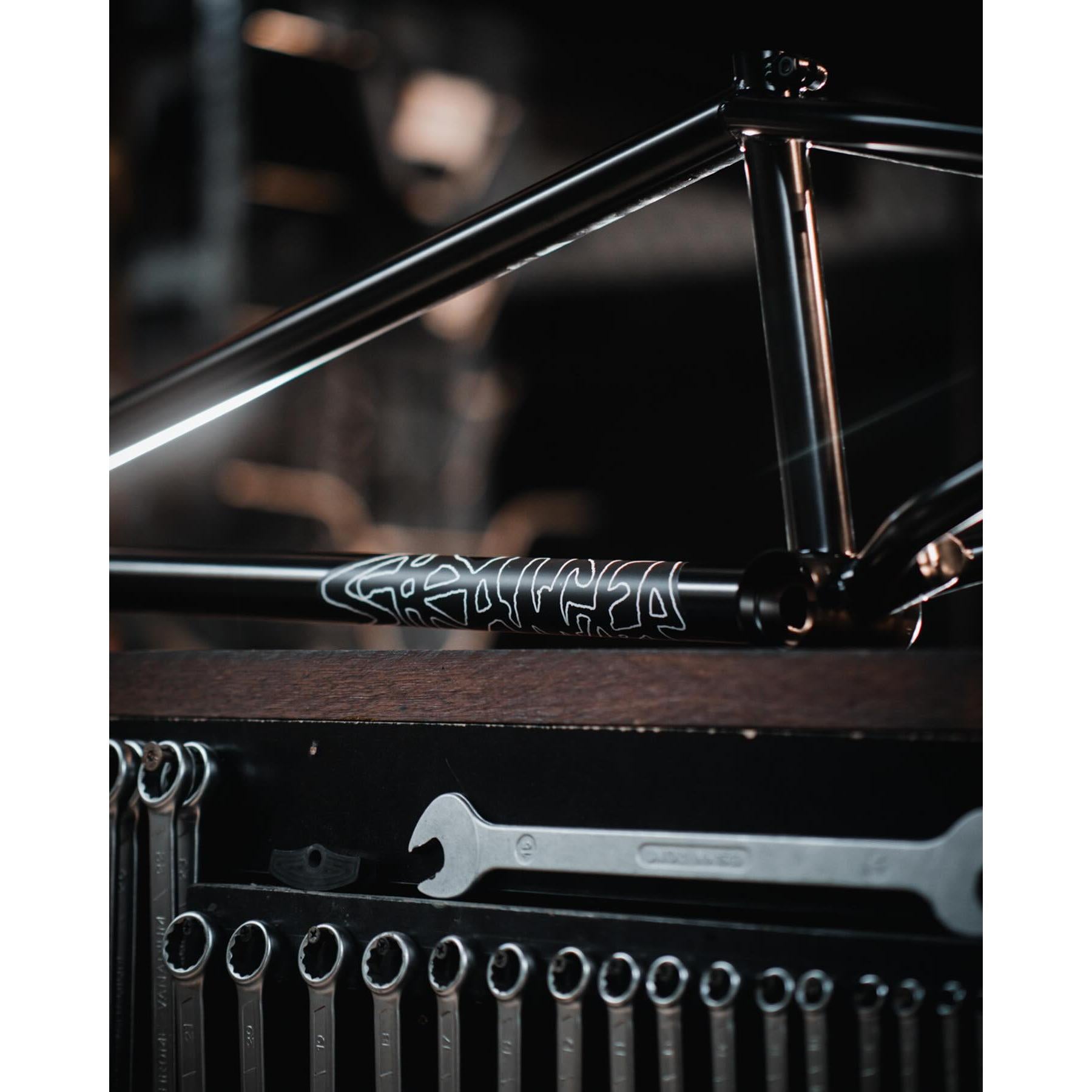 A partially assembled Stranger Royale Frame, constructed from durable Chromoly tubing, is positioned above a pegboard with various wrenches hanging below it.