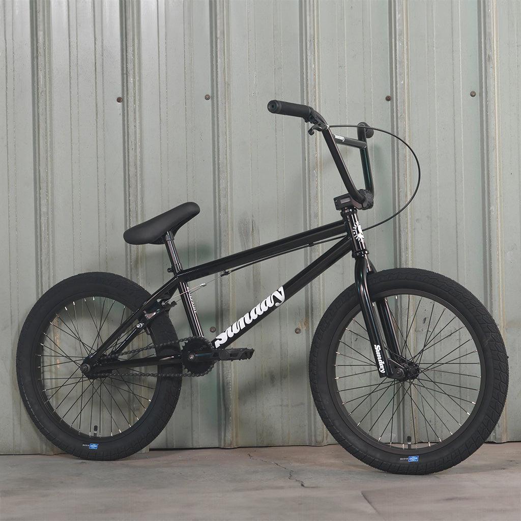 A blue Sunday Blueprint 20 inch bike leaning against a wall.