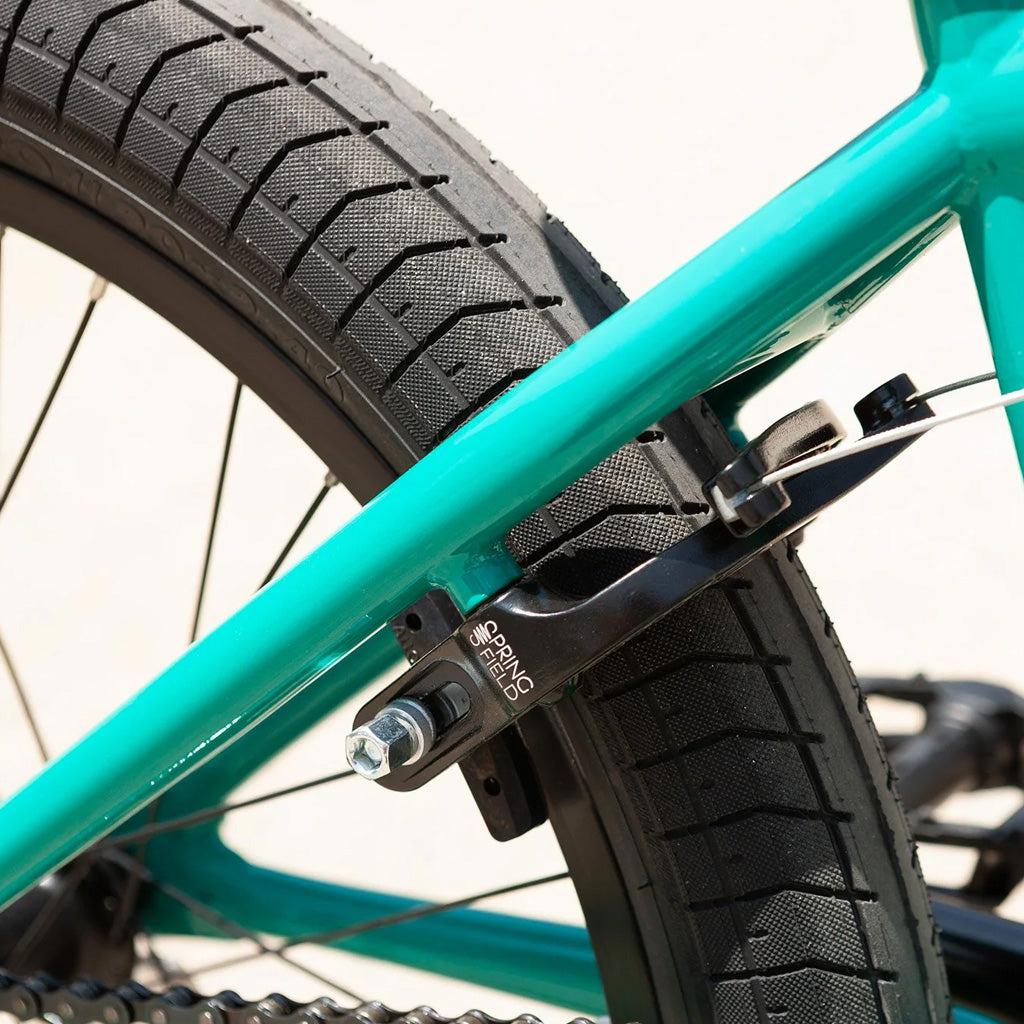 Close-up of a Sunday Primer 20 Inch Bike wheel with a teal frame and a black spring brake system mounted on the rear wheel, showcasing pro-level geometry.