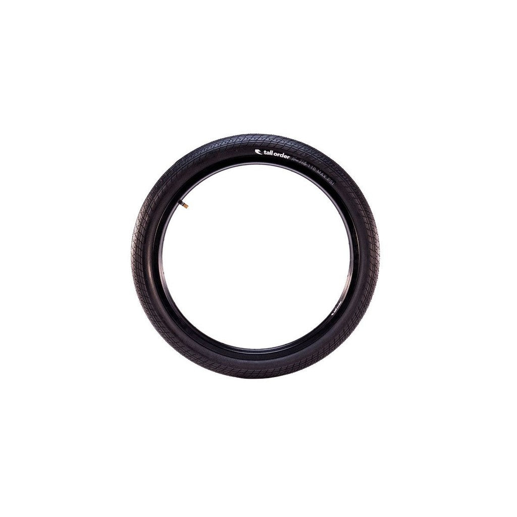 A single Tall Order Reilly Park 20 Inch Tyre in black, featuring a visible tread pattern, is displayed upright against a plain white background, echoing the high-performance style of Kieran Reilly’s signature tyres.