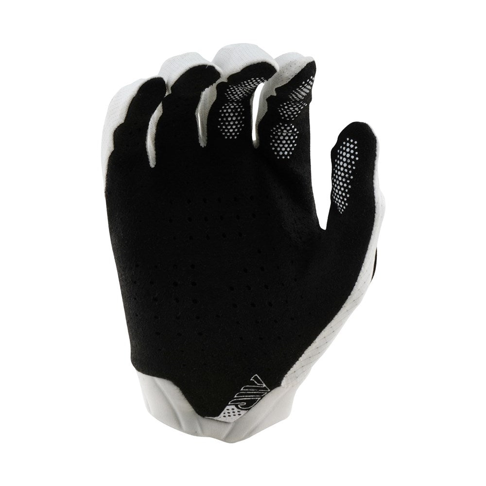 The TLD 25.1 Air Glove Mono White features a sleek black and white design with textured grip, breathable material, and micro-mesh ventilation. A geometric logo on the wrist blends functionality with style.
