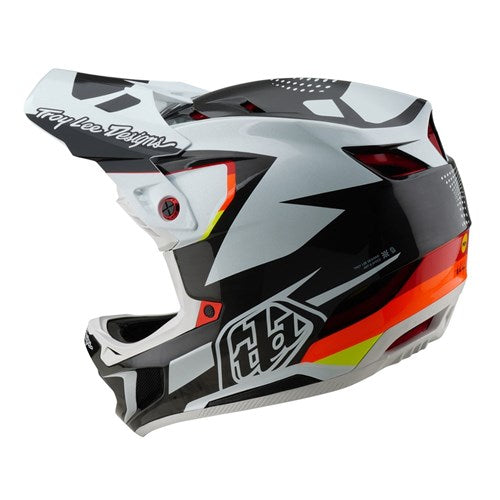 The TLD 25.1 D4 Carbon Helmet (MIPS) features an optic black, white, and orange geometric design with a visor and "Troy Lee Designs" text on top. Ideal for downhill BMX, it offers ultimate protection with D4 Carbon MIPS technology.