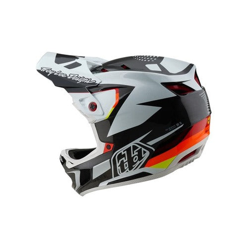 The TLD 25.1 D4 Carbon Helmet (MIPS) features an optic black, white, and orange geometric design with a visor and "Troy Lee Designs" text on top. Ideal for downhill BMX, it offers ultimate protection with D4 Carbon MIPS technology.