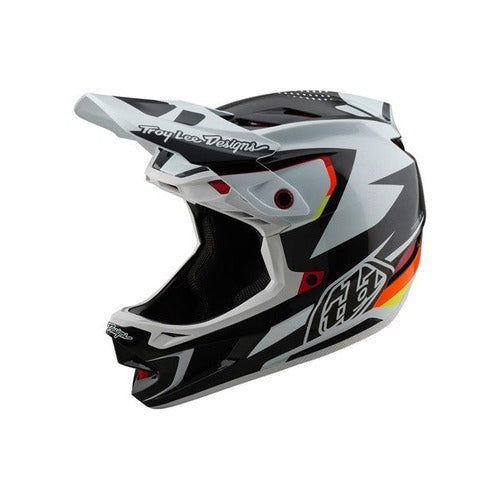 The TLD 25.1 D4 Carbon Helmet (MIPS) in Optic Black showcases striking black, white, and orange angular patterns with the "Troy Lee Designs" logo on top, making it ideal for downhill BMX enthusiasts desiring style and protection.