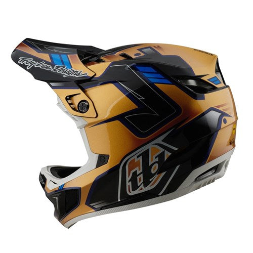 The TLD 25.1 D4 Composite Helmet (MIPS) in Royalty Black/Gold boasts a geometric design with gold, blue, and black. It features the advanced Mips® C2 system for protection, along with a visor and ventilation openings for a stylish and safe ride.