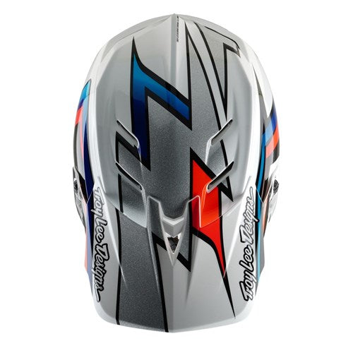 Top view of the TLD 25.1 D4 Composite Helmet (MIPS) in white and silver, featuring geometric patterns with red and blue accents, "Troy Lee Designs" text, and MIPS Protection for enhanced safety.