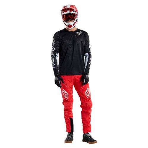 Person wearing a TLD 25.1 Sprint Jersey / Mono Black with helmet, goggles, gloves, long-sleeve shirt, and pants, standing against a plain white background.