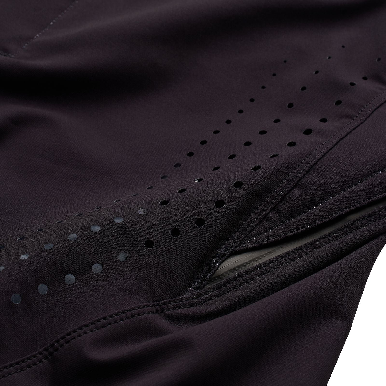 A close-up of the TLD 25.1 Youth Sprint Pant Mono Black displays black BMX racing fabric with perforated holes, a hidden pocket, intricate stitching, and durable material texture.