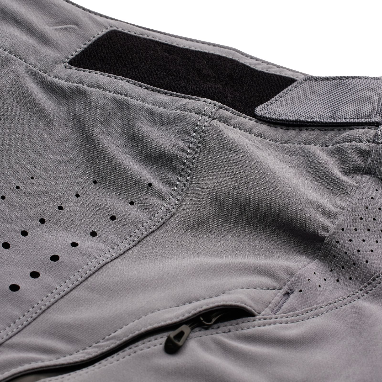 Close-up of a gray TLD Youth Sprint Pant Mono Charcoal with ventilation holes and a zippered section, designed for BMX racing.
