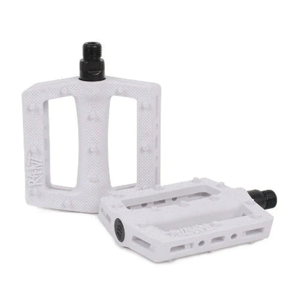 The Rant Trill Plastic Pedals are white rectangular pedals with textured surfaces and sturdy chromoly axles, shown with one upright and one flat—ideal for upgrading your BMX ride.