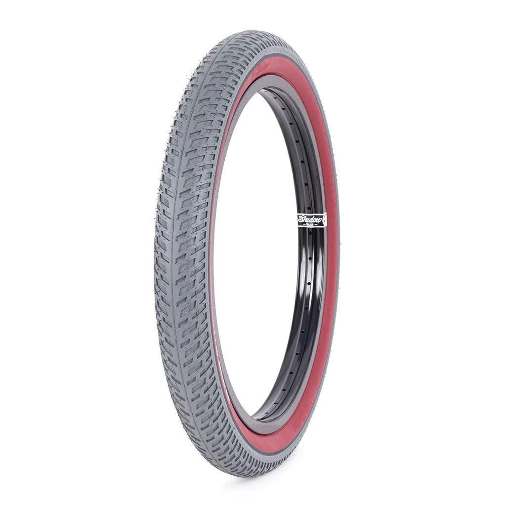 The Shadow Conspiracy Contender Welterweight Tyre features a slim profile with black tread, red sidewall, and black inner rim. Designed for all-around use, it's shown upright against a white background.