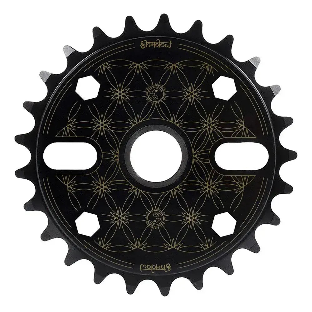 Shadow Sabotage Maya Edition V2 Sprocket: Black BMX sprocket with Joris Coulomb signature, gold geometric lines, 6 hex holes, and 2 slots near the center.