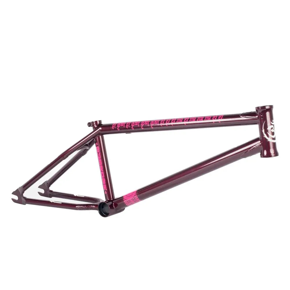 A maroon Subrosa OM V2 Frame with pink accents and graphics is shown from the side against a white background. This frame offers a unique blend of style and performance in Joris Coulomb's signature design.