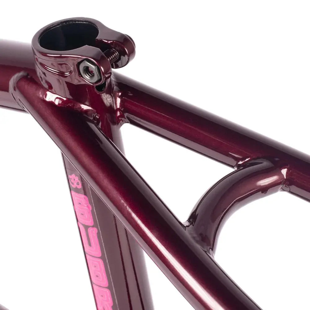 Close-up view of a metallic red Subrosa OM V2 Frame with a seat clamp and pink lettering on the down tube, featuring the Joris Coulomb signature design.