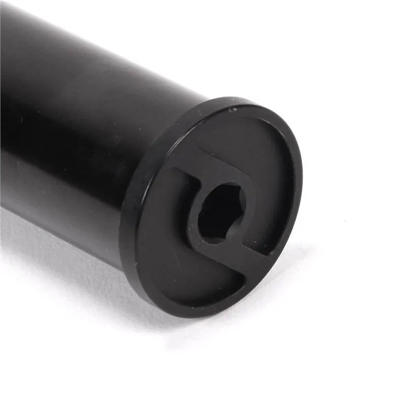 Close-up of a black cylindrical metal rod, identified as a Primo Balance Fork, featuring a hexagonal hole and two opposing slots at one end. The fork is crafted from heat-treated chromoly and is shown resting on a white surface.