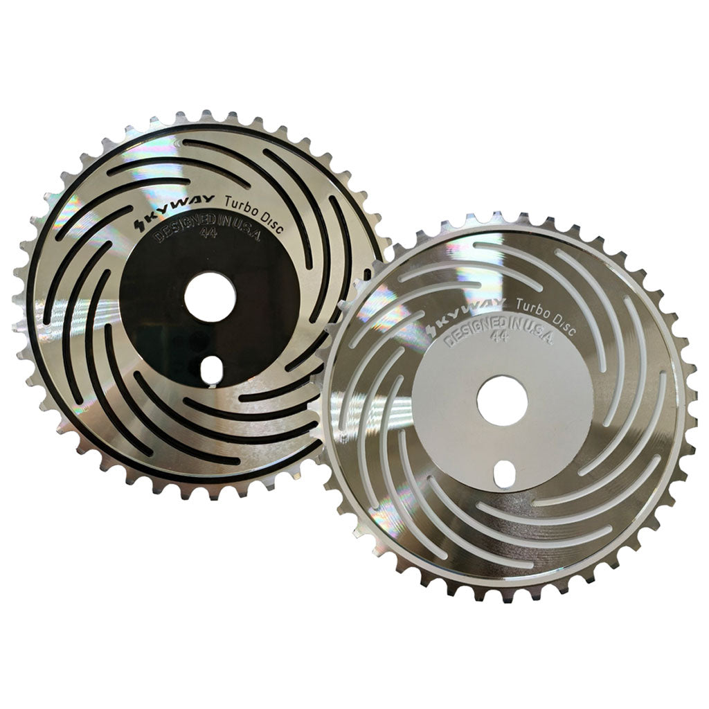 Two silver, circular saw blades with patterned slots, labeled "Skyway Turbo Disc Front Sprocket." CNC machined from 6061 Aluminum alloy, the blades are positioned vertically, slightly overlapping, displaying their reflective surfaces.