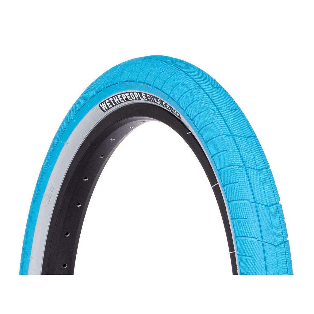 The WeThePeople Activate Tyre, featuring an eye-catching bright blue color, boasts a black rim and striking white sidewall text that reads "Wethepeople Cliche 20 x 2.4." Its nylon-reinforced sidewall and high-pressure capabilities make it ideal for both style and performance.