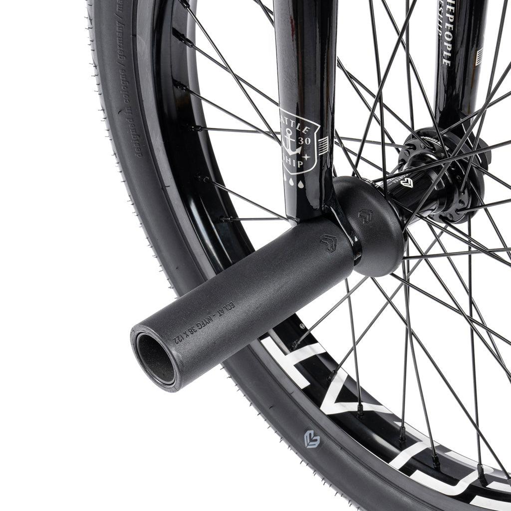Close-up of the Wethepeople Battleship 20 Inch Bike's black BMX front wheel, highlighting the spokes, tire, and metal peg on the axle for tricks. Eclat components ensure enhanced durability.