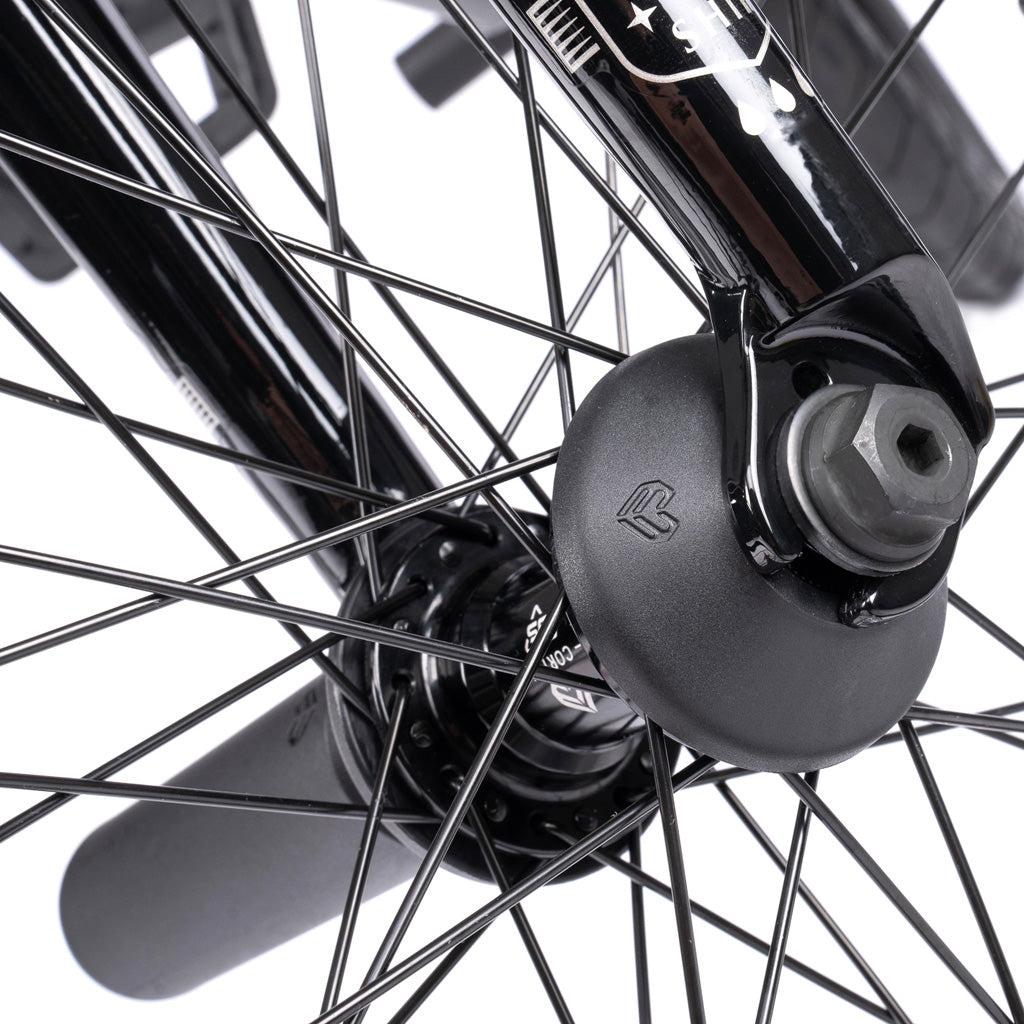 Close-up of the Wethepeople Battleship 20 Inch Bike wheel, featuring black spokes, axle bolt, hub, and a protective hub guard near the fork with quality Eclat components.