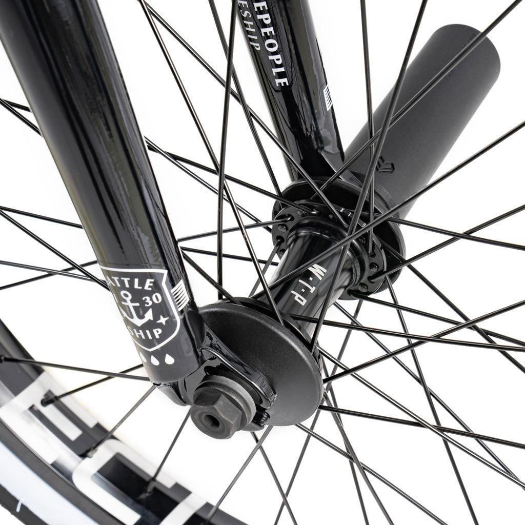 Close-up of the Wethepeople Battleship 20 Inch Bike’s front wheel featuring black spokes, fork, axle, branding labels, and visible Eclat components.