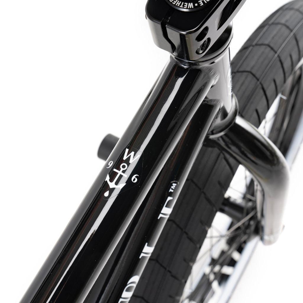 Close-up of the Wethepeople Battleship 20 Inch Bike, a black BMX with a Chromoly frame, front fork, partial tire, and a white anchor graphic featuring the numbers "9" and "6" on a white background.