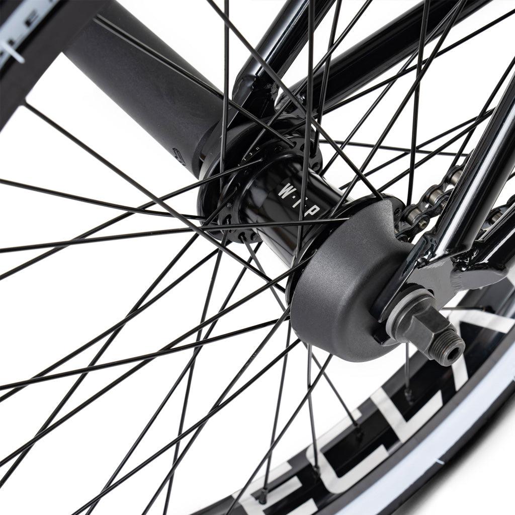 Close-up of a Wethepeople Battleship 20 Inch Bike wheel with black spokes, a metal hub, and part of the rim featuring a white pattern and quality Eclat components.