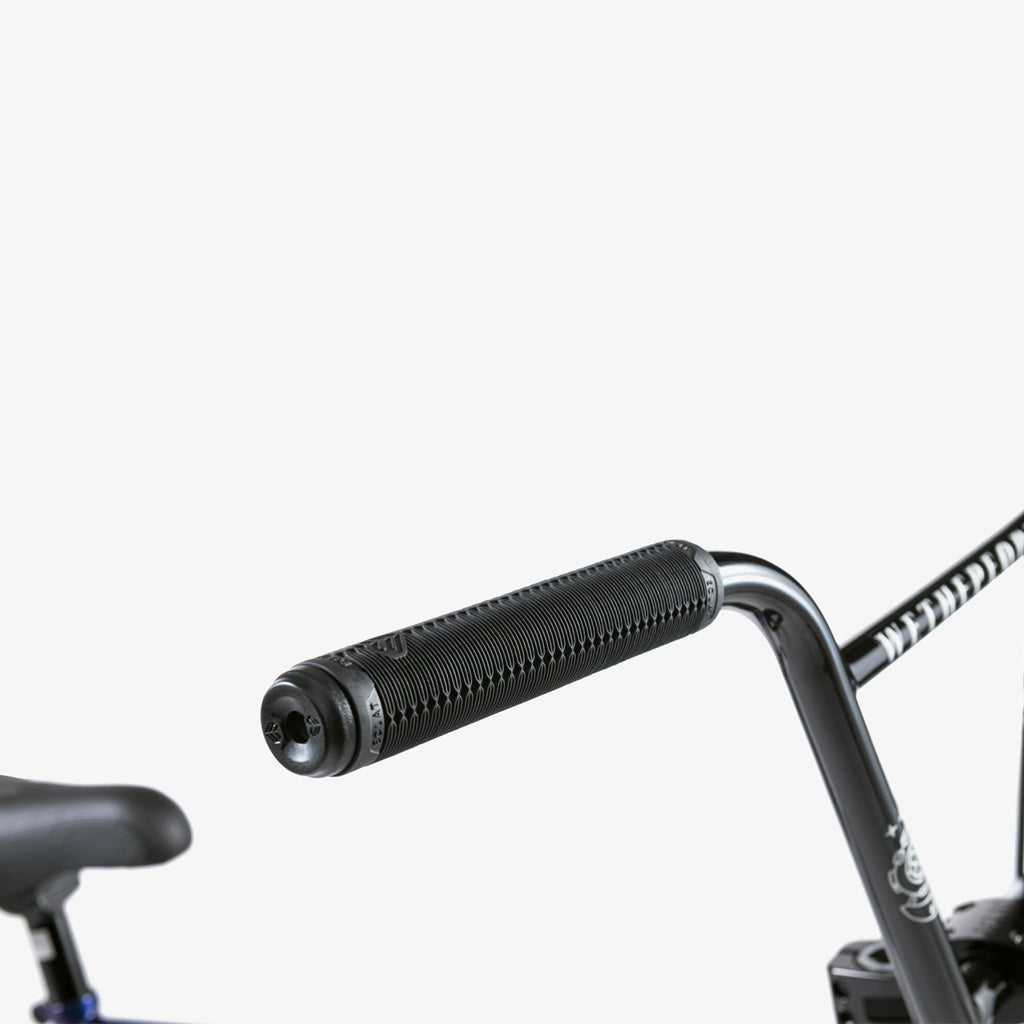 Close-up of the Wethepeople Battleship 20 Inch Bike's black BMX handlebar with textured rubber grip, featuring Eclat components and part of the seat in view against a plain white background.