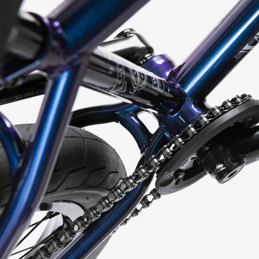 Close-up of the Wethepeople Battleship 20 Inch Bike’s rear tire, chain, and crankset, emphasizing its metallic blue Chromoly frame and drivetrain parts against a white background.