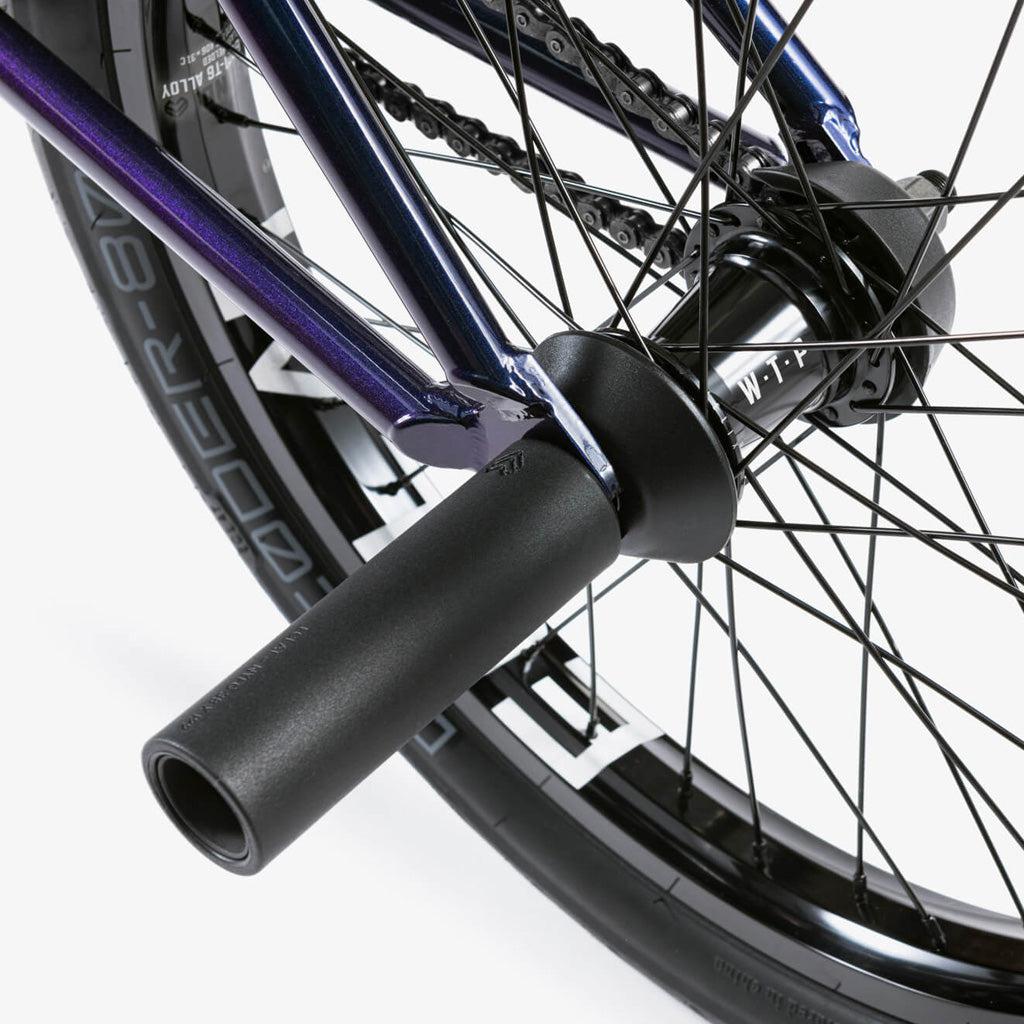Close-up of the Wethepeople Battleship 20 Inch Bike's rear wheel, highlighting black spokes, axle pegs, part of the frame with chain, Eclat components, and tire branding.