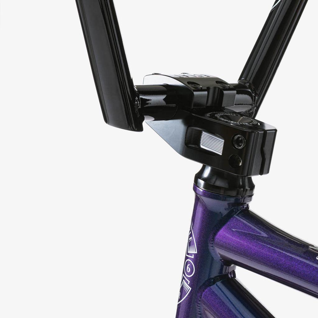 Close-up view of the handlebar stem and headset featuring Eclat components on a Wethepeople Battleship 20 Inch Bike with a metallic purple chromoly frame, set against a white background.