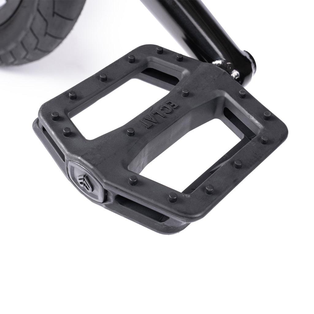 Close-up of a black bicycle pedal attached to a crank arm on the Wethepeople Battleship 20 Inch Bike, with part of the bicycle tire visible in the background.
