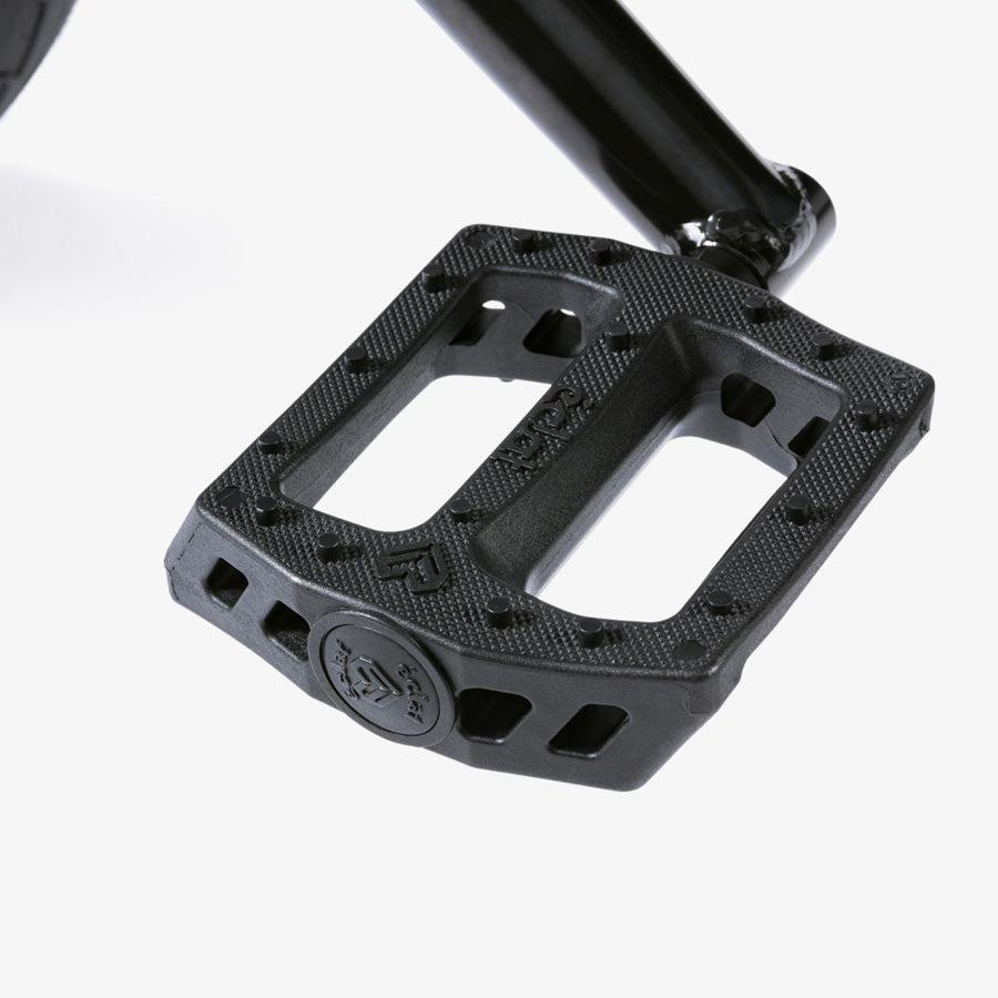 Close-up of a black plastic pedal on a metal crank arm, set against a plain background—ideal for the Wethepeople CRS 18 Inch Bike, one of the best 18 inch BMX bikes made for young riders.